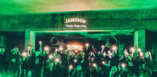 Grupa ludzi pozująca do zdjęcia w ciemnym pomieszczeniu oświetlonym na zielono