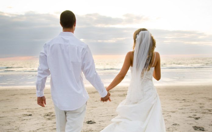 Para nowożeńców spacerująca plażą