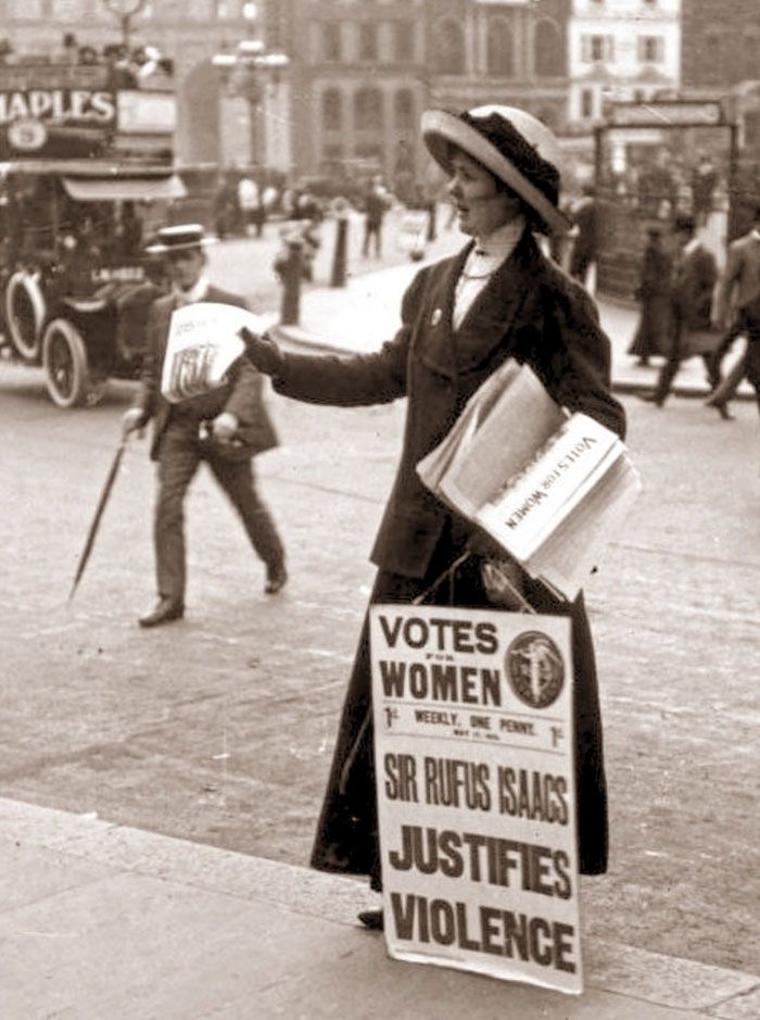 Zdjęcie w sepii pokazujące kobietę w płaszczu z tabliczką Vote for Women