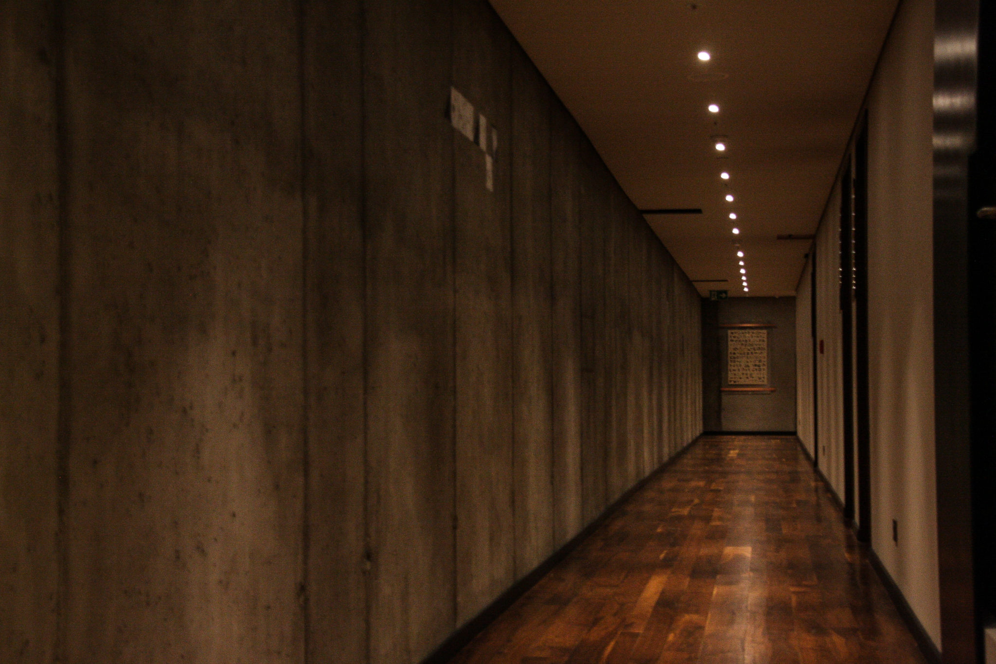 Długi korytarz z drewnianą podłogą i minimalnym światłem