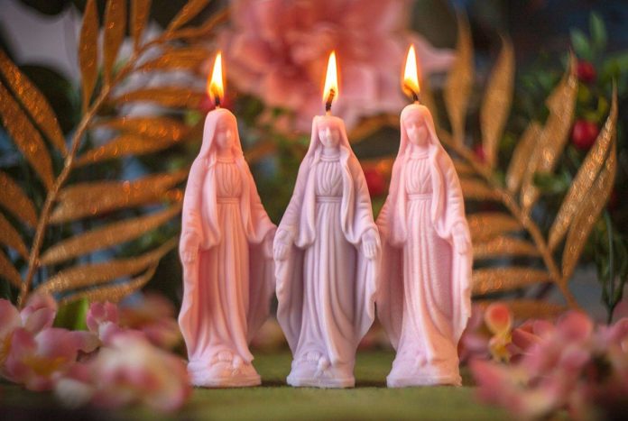 Świeczki w kształcie figurek Maryi na tle zieleni