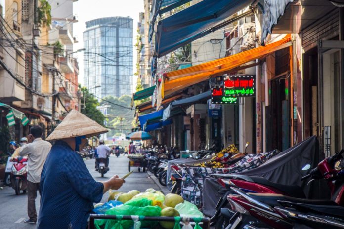 Widok uliczki w wietnamie: widać skutery i kobietę w kapeluszu