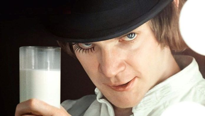 Mężczyzna w czarnym kapeluszu i białej koszuli ze szklanką mleka w dłoni