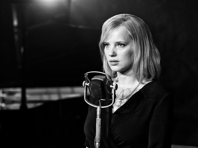 Czarno-białe zdjęcie kobiety stojącej przy mikrofonie