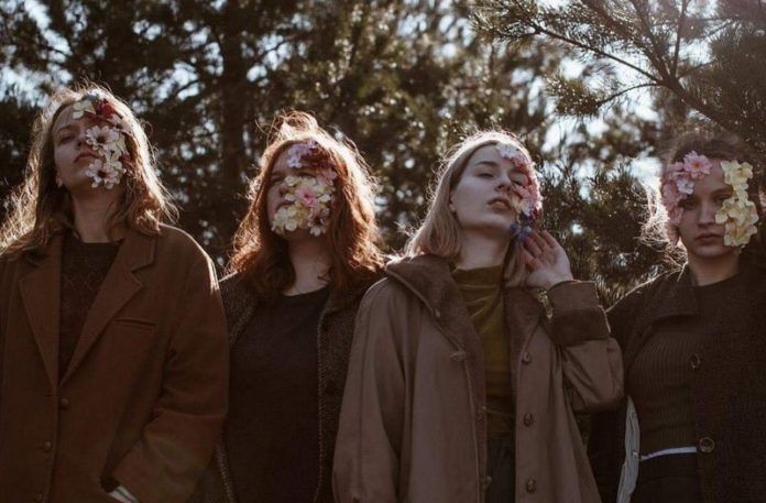 Cztery dziewczyny stojące w parku z kwiatami na twarzy