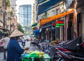 Widok uliczki w wietnamie: widać skutery i kobietę w kapeluszu