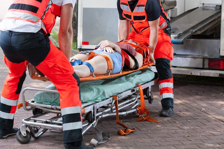 dwaj ratownicy medyczni wnoszą rannego do karetki