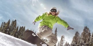 Dziewczyna w zielonej kurtce na snowboardzie