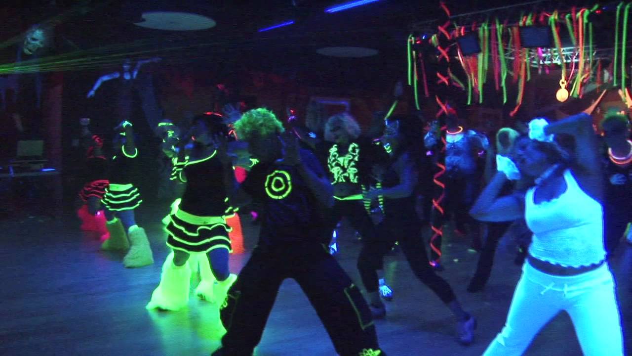 Ludzie ubrani we fluorescencyjne ubrania bawiący się na imprezie