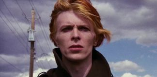 Rudowłosy mężczyzna z rozwianymi włosami, w tle błękitne niebo