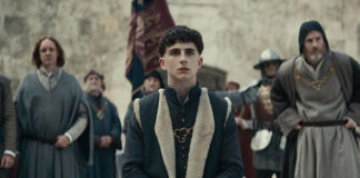 Kadr z filmu The King, w centrum siedzi ubrany w średniowieczny strój Timothee Chalamet, grający główną postać księcia Hala
