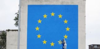 Flaga Unii Europejskiej i mężczyzna odłupiający jedną gwiazdę