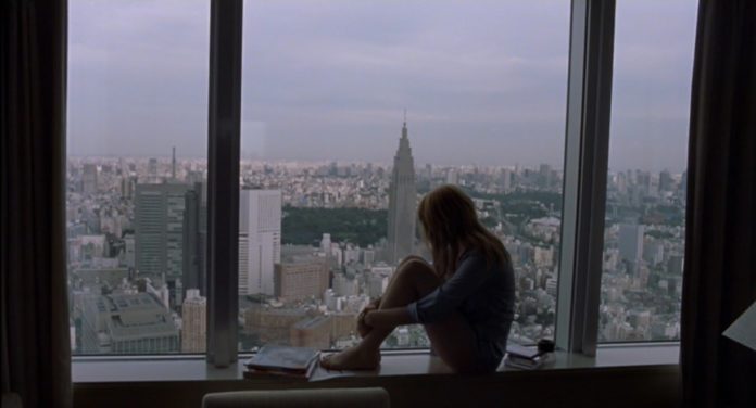 Kobieta siedząca na parapecie okna (Scarlett Johanson) wpatrzona w panoramę Tokyo