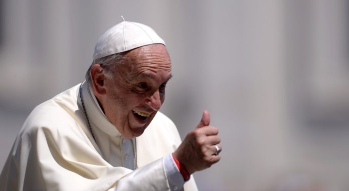 Zdjęcie przedstawia papieża franciszka, uśmiechniętego, pokazującego 