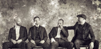 Czarno-białe zdjęcie przedstawiające czwórkę ludzi na krzesłach