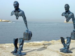 Zdjęcie przedstawia rzeźbę z brązu ukazującą dwoje podróżnych, z pustką w centrum jego postaci