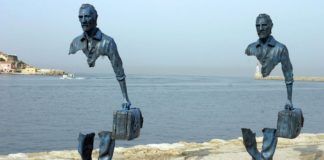 Zdjęcie przedstawia rzeźbę z brązu ukazującą dwoje podróżnych, z pustką w centrum jego postaci