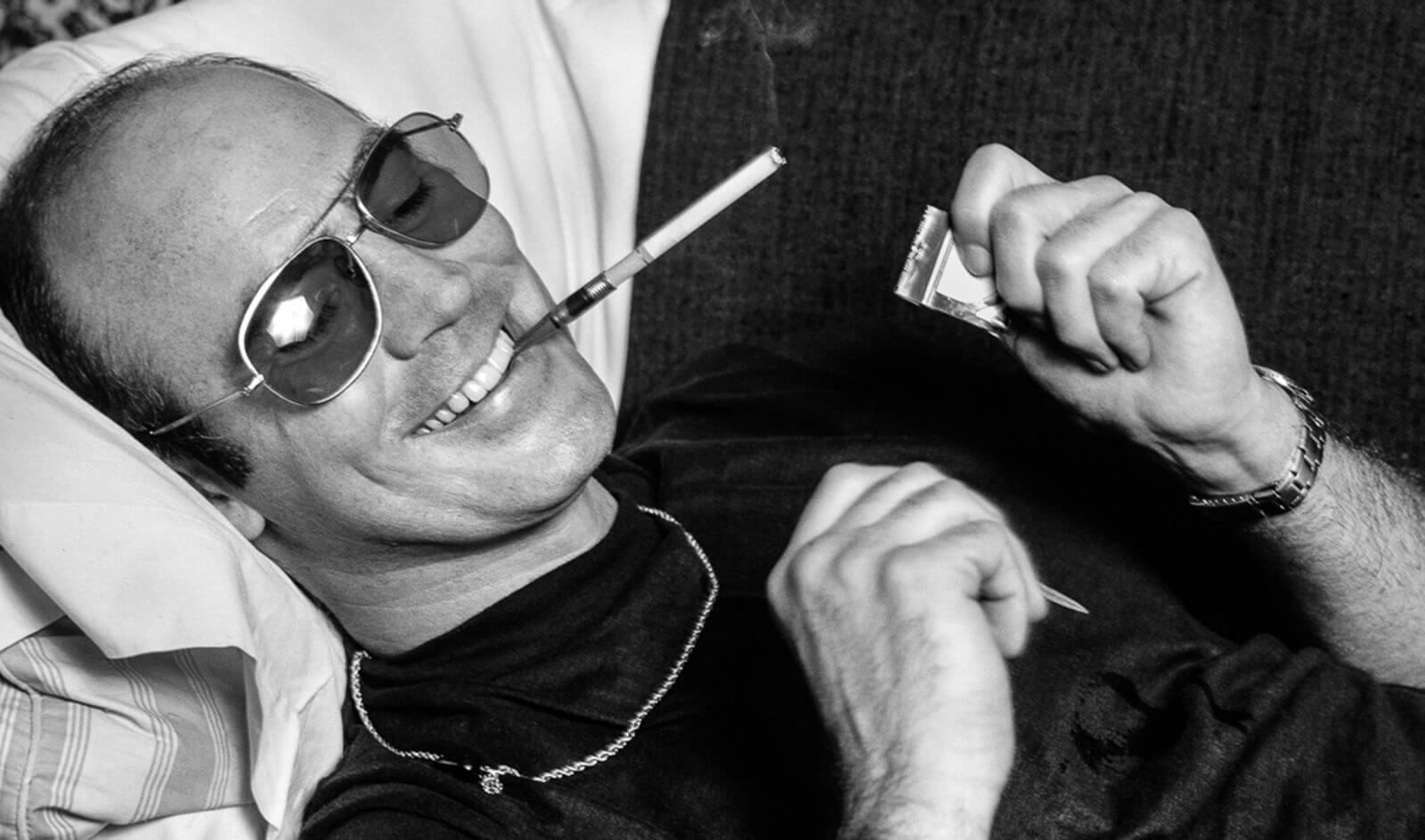 Pisarz Hunter S. Thompson leżący w okularach przeciwsłonecznych z papierosem