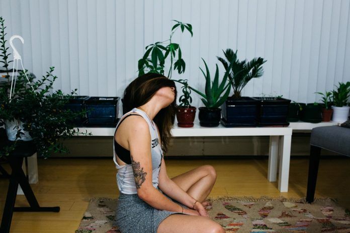 Dziewczyna z tatuażami ćwiczy na dywanie