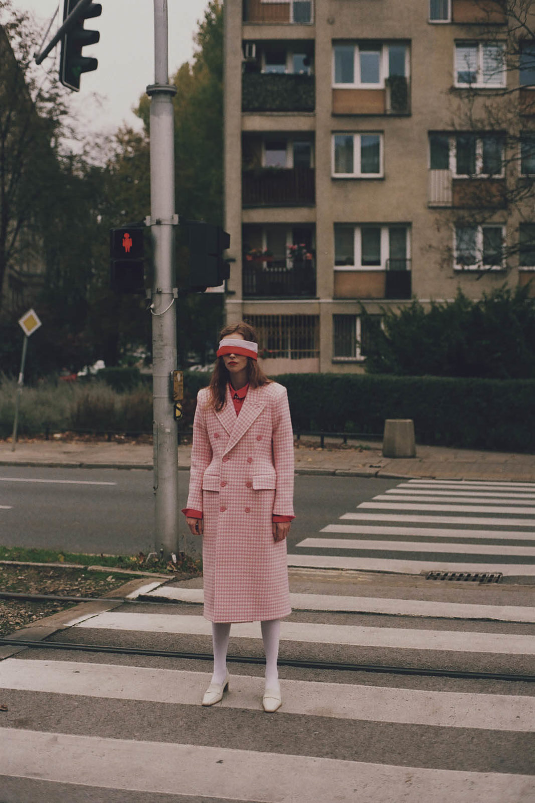 kobieta z biało czerwoną przepaską na oczach stoi na przejściu dla pieszych